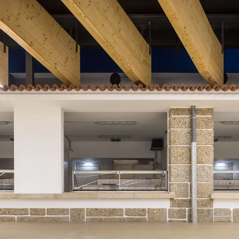 Elevated terrace with cork-tiled planters beneath exposed glulam beams and terracotta tile parapet at dusk