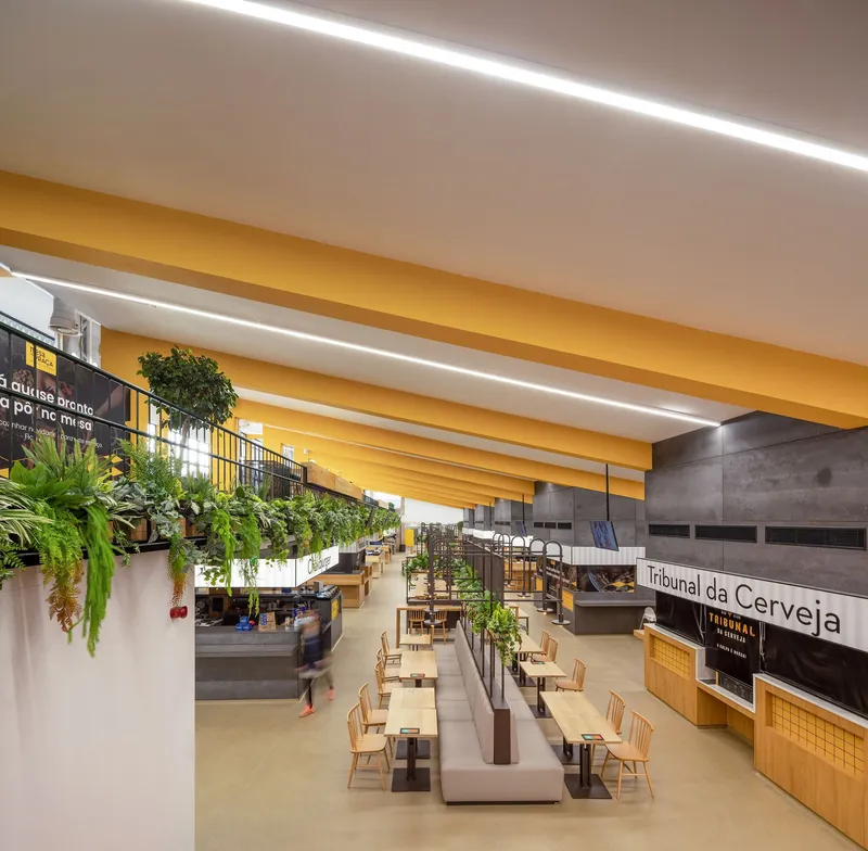 Food hall seating area with yellow ceiling beams, hanging planters and polished concrete floor