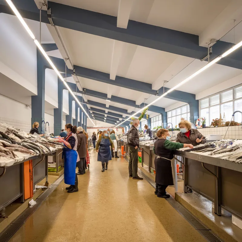 Fish market hall with blue and white painted beams, stainless counters and workers in aprons