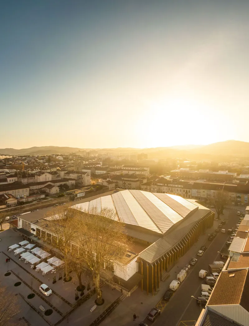 Elevated view of the metal roof and timber colonnade at sunset with mountains beyond