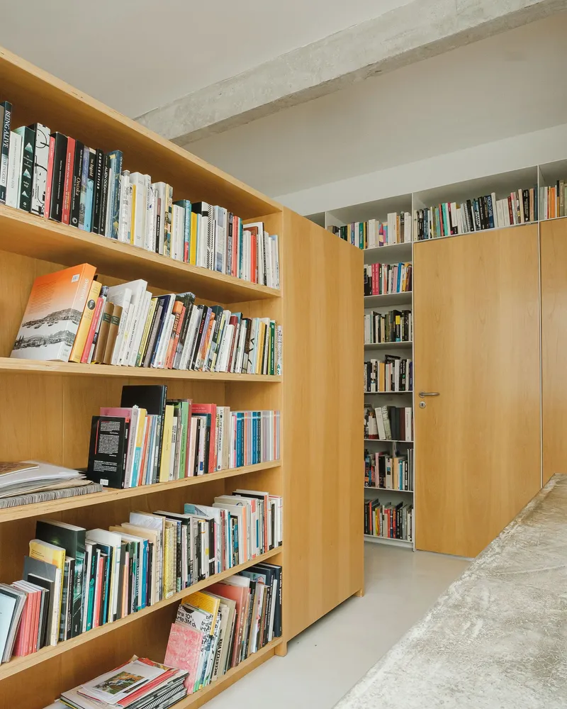 Blonde wood bookshelves with exposed concrete beam ceiling and polished concrete floor