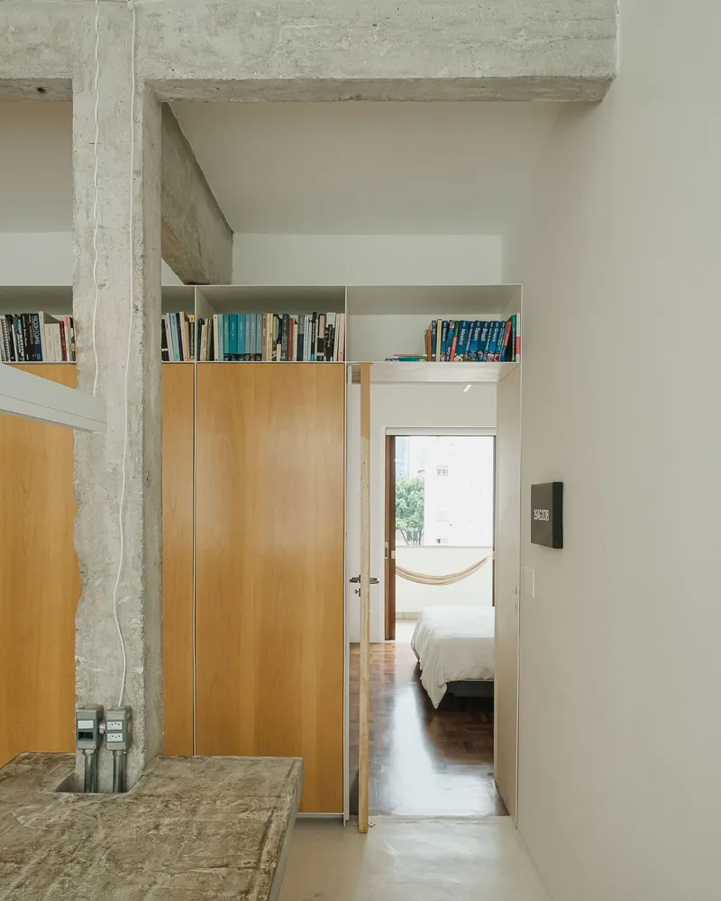 Hallway view through open doorway to bedroom with hammock and exposed concrete column