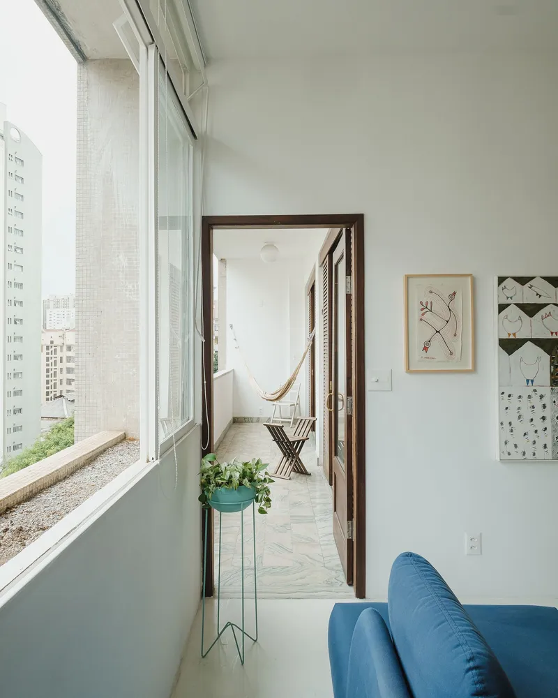 Glazed balcony opening to narrow terrace with hammock and views to neighboring buildings