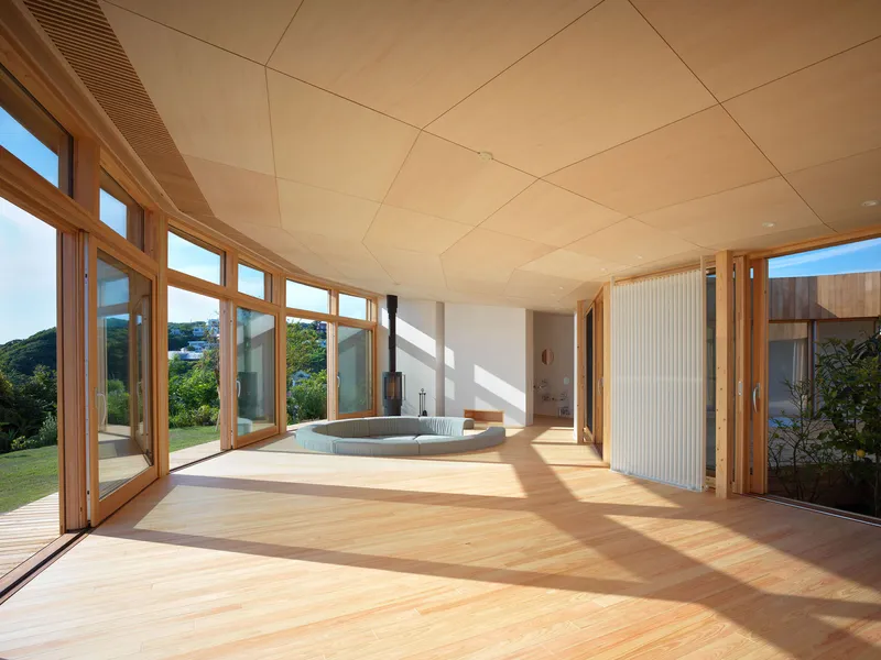 Interior room with curved timber-framed glazing and sunken bath flooded with afternoon light