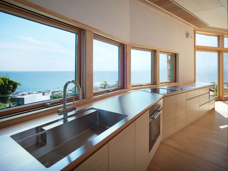 Kitchen with stainless steel countertop and timber-framed windows overlooking the ocean