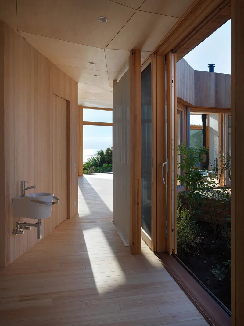 Hallway with timber-lined walls and glazed doors opening to a planted courtyard
