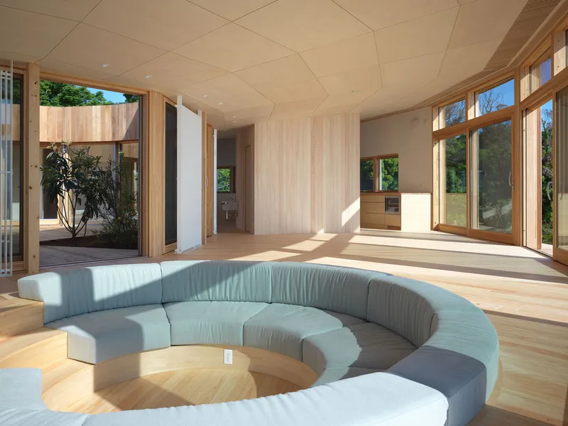 Living room with circular sunken seating and plywood ceiling panels in afternoon sunlight