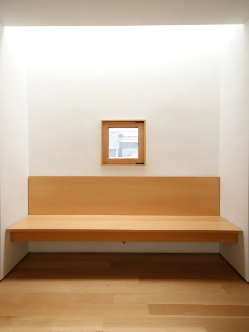 Built-in timber bench set into white alcove beneath a framed window