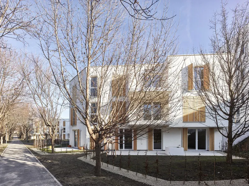 White corner building with timber shutters framed by pollarded trees in winter