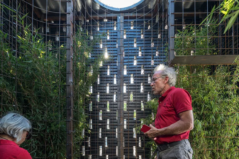 Interior view of the planted green walls flanking the woven timber screen with visitors below