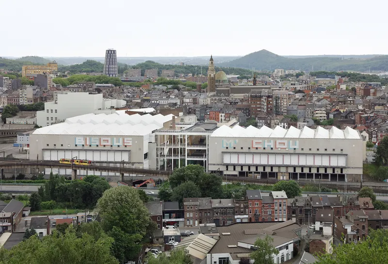 Aerial view of the white panel and glass facade rising above rooftops in the city