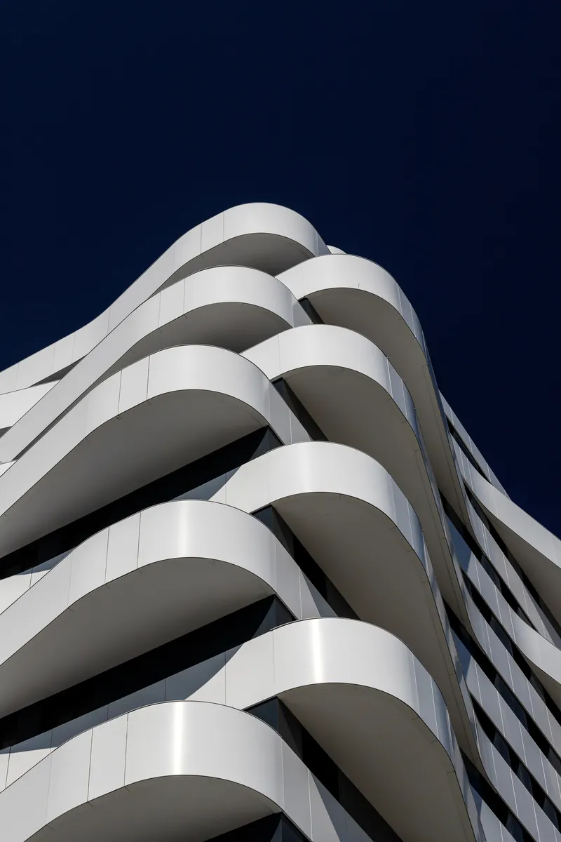 Corner detail of the spiraling white balcony edges against a dark evening sky
