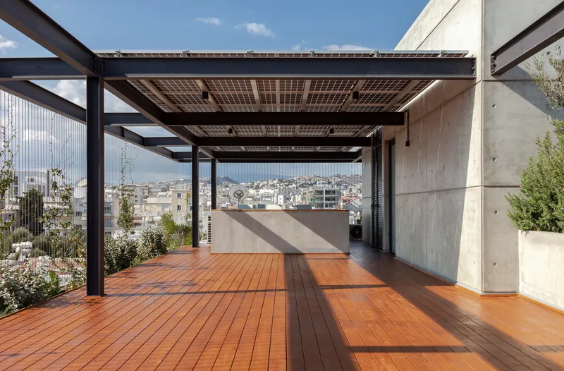 Rooftop terrace with solar panel canopy on steel beams above timber decking and concrete walls