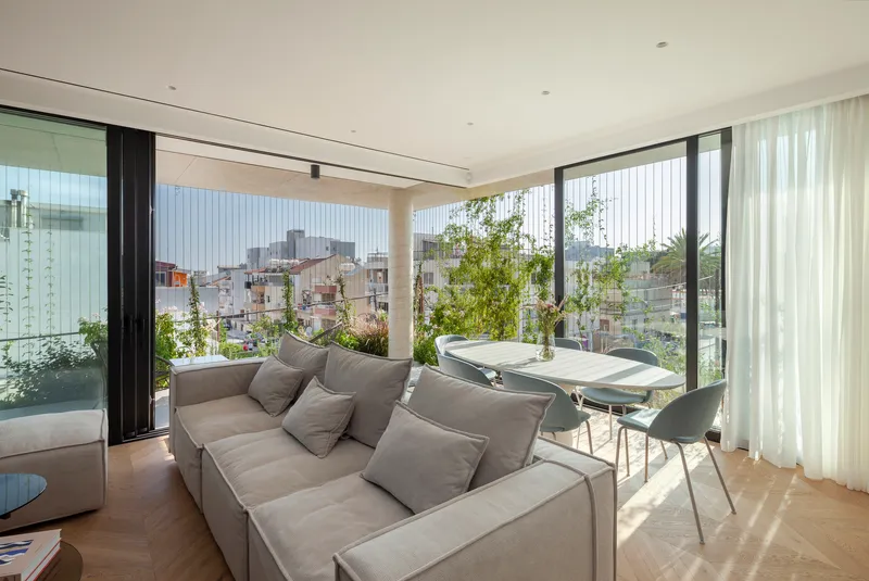 Living room opening onto terrace with vertical green screen and views across the low-rise neighborhood