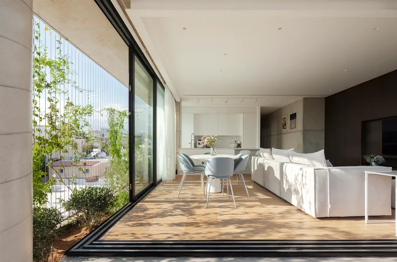 Interior living space with sliding glass doors opening to planted balcony with cable-mounted vines in sunlight