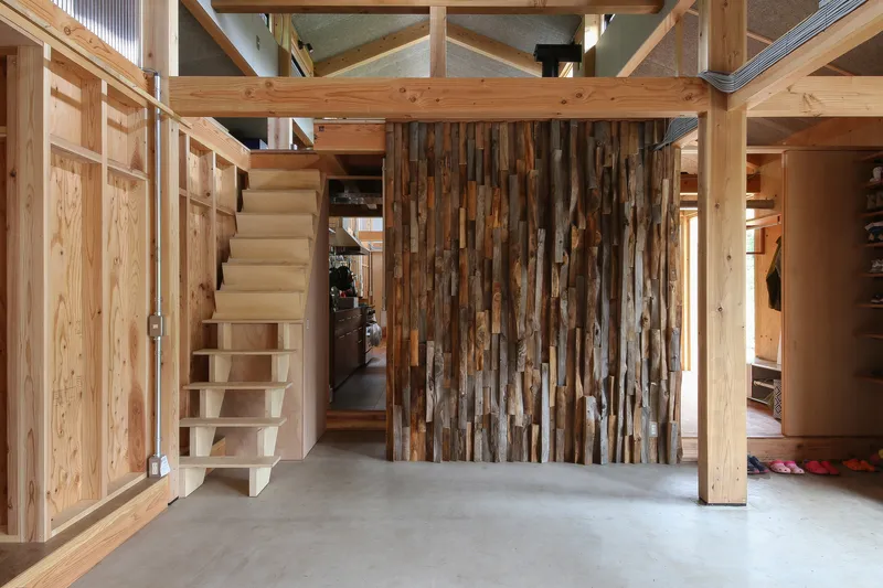 Entry hall with alternating timber board partition wall, floating plywood stair and polished concrete floor