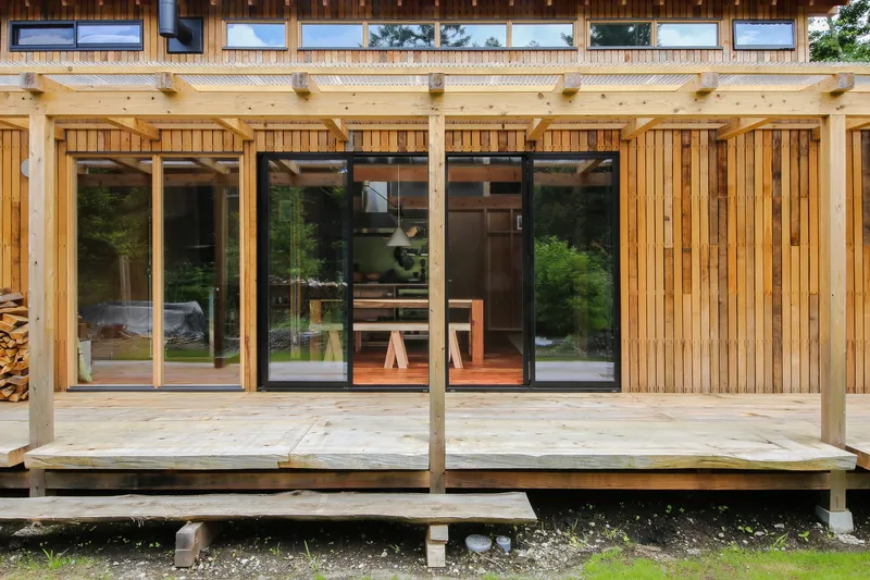 Timber deck with sliding glass doors flanked by vertical wood slat cladding and clerestory windows above