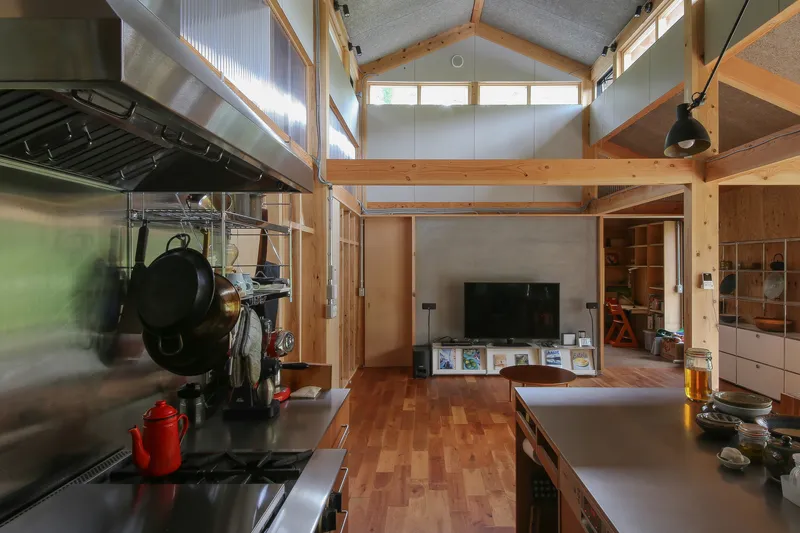 Open kitchen and living space with exposed timber frame and clerestory windows filtering daylight