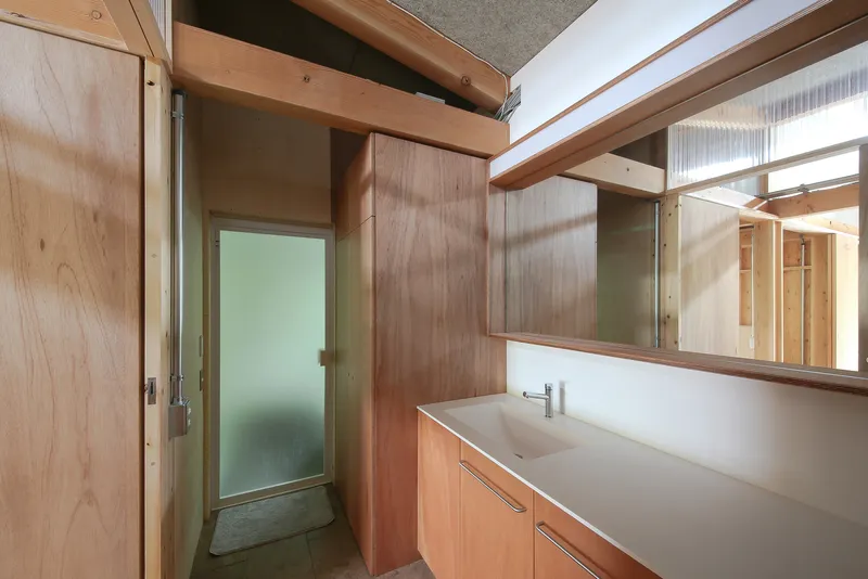 Bathroom vanity with integrated sink and frosted glass door reflecting light from adjacent clerestory windows