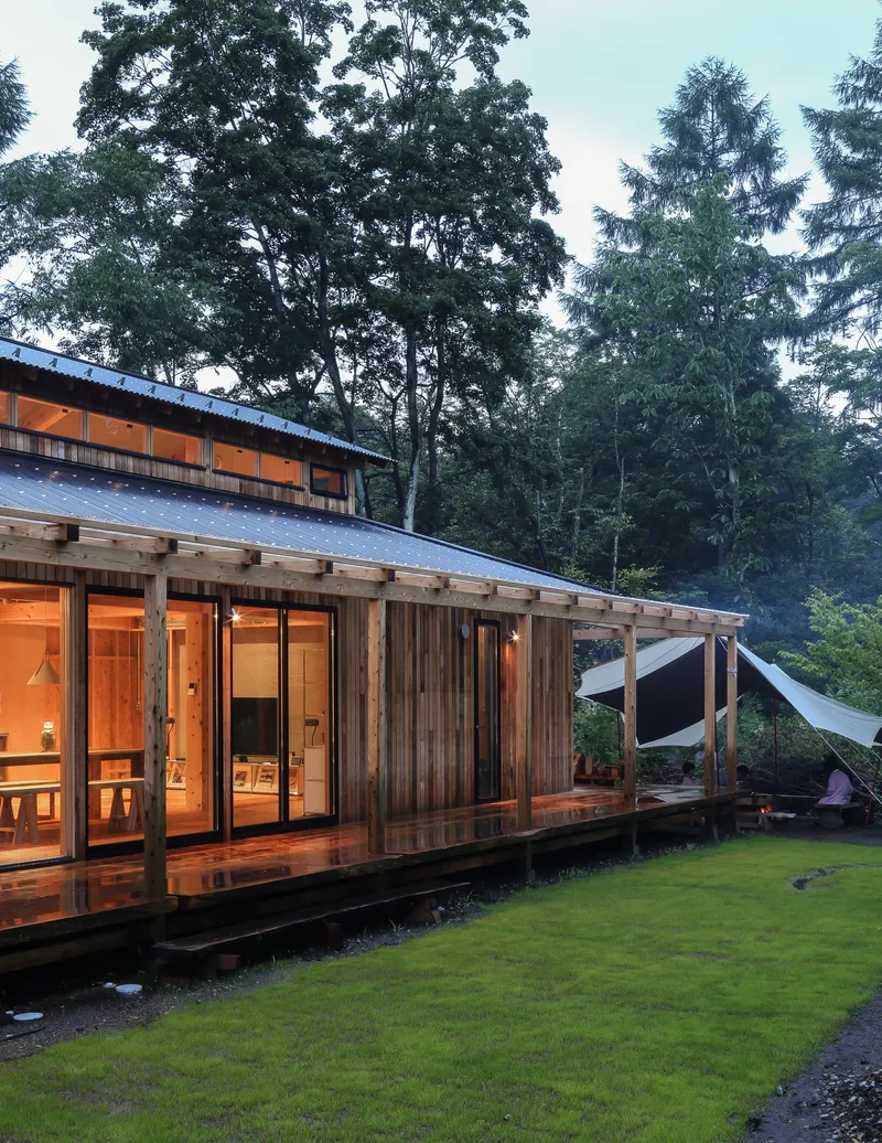 Exterior view of the timber-clad volume with covered deck and glazed doors at dusk