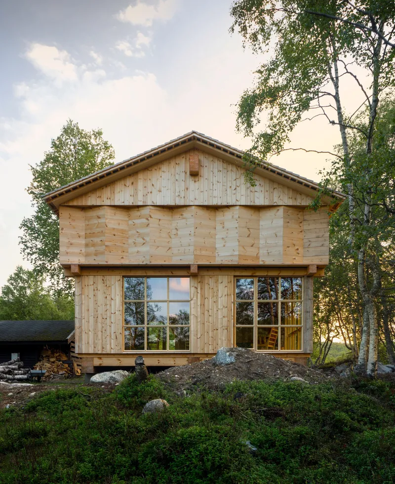 Horizontal timber plank facade with paired windows and projecting eaves under afternoon light