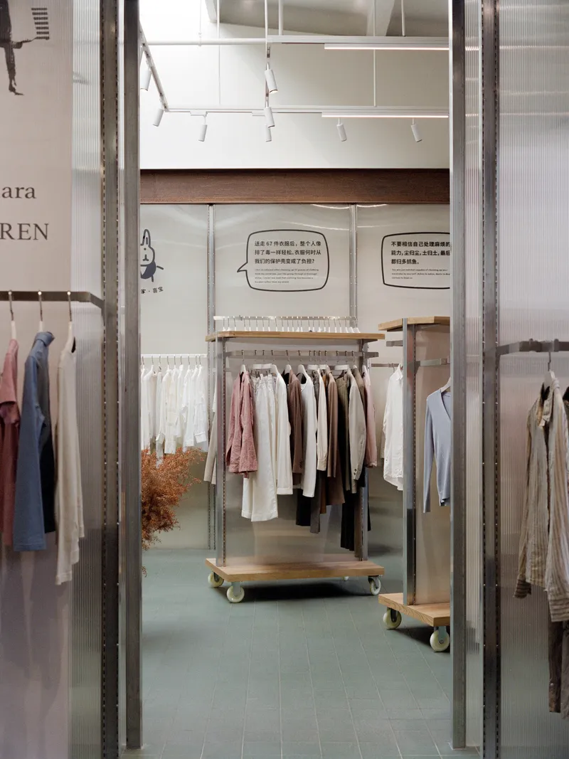 View through galvanized steel partition frames into a retail space with wheeled garment racks