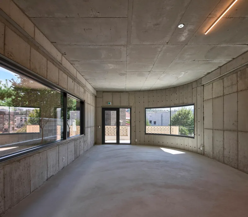 Interior room with board-formed concrete walls and ceiling illuminated by recessed linear lighting