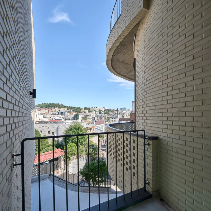 Upper level balcony framed by white brick walls with views across a residential hillside neighborhood