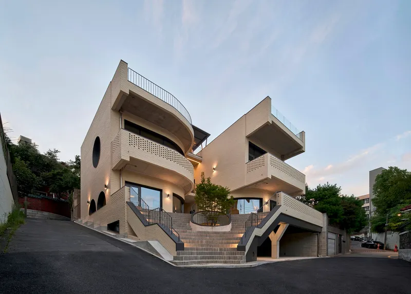 Facade with arched openings and cantilevered concrete slabs flanked by external stairs at dusk