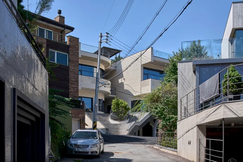 Street view showing terraced brick facades with curved balconies and overhead power lines