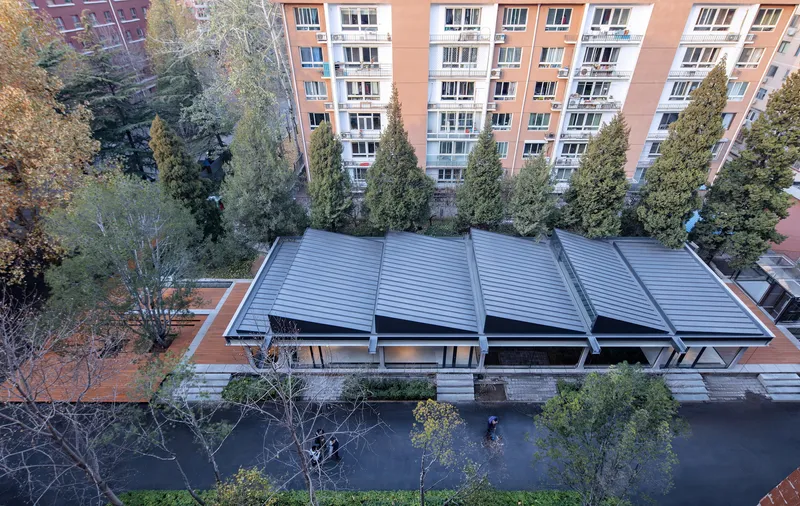 Aerial view of four parallel barrel vault roofs set between residential buildings and bare winter trees