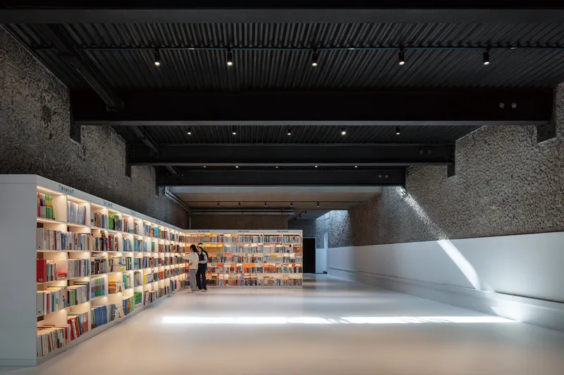 Interior reading room with backlit bookshelves and textured stone walls under a ribbed black ceiling
