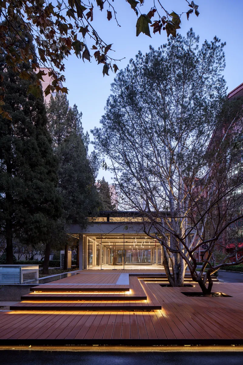 Tiered timber deck with integrated linear lighting leading to the glazed pavilion at dusk