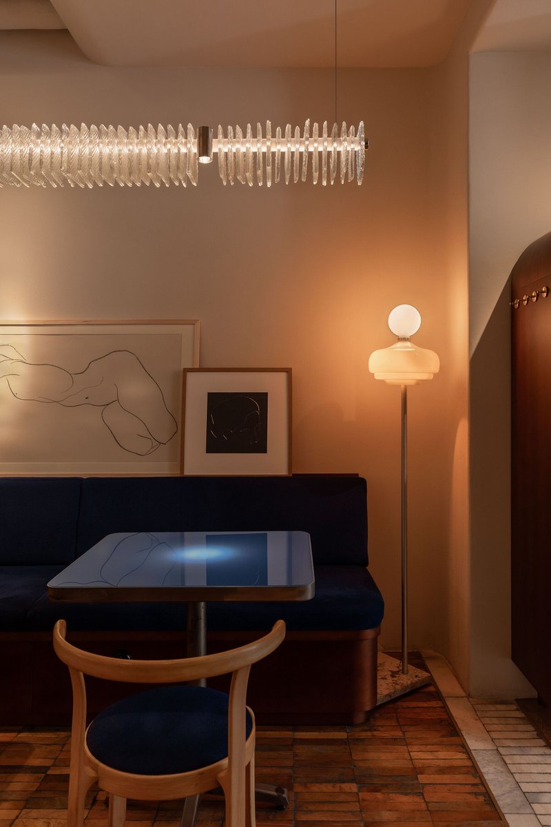 Interior dining nook with navy banquette seating, sculptural pendant light and warm wood flooring