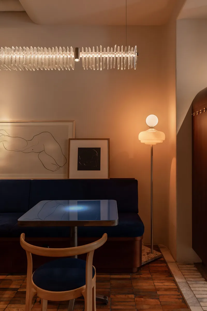 Interior dining nook with navy banquette seating, sculptural pendant light and warm wood flooring