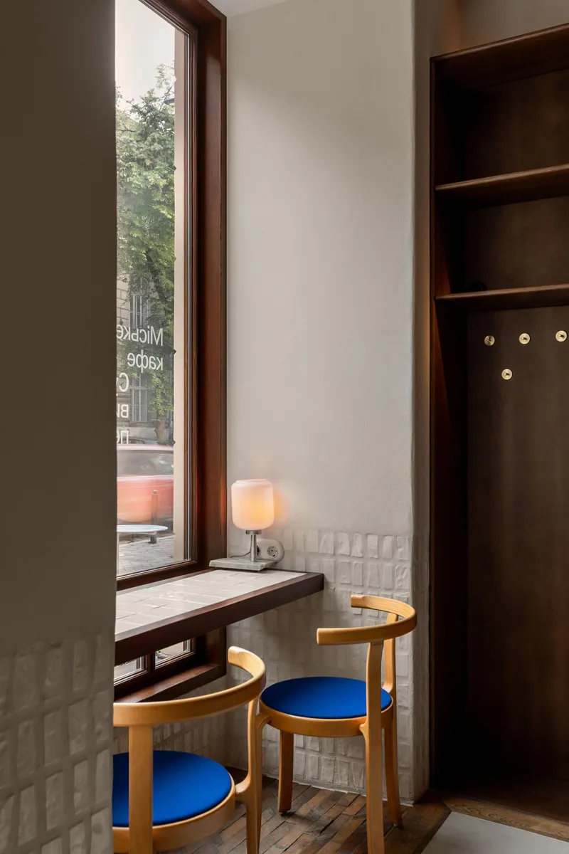 Window seat with dark wood frame, white quilted tile wainscoting and wooden chairs with blue cushions