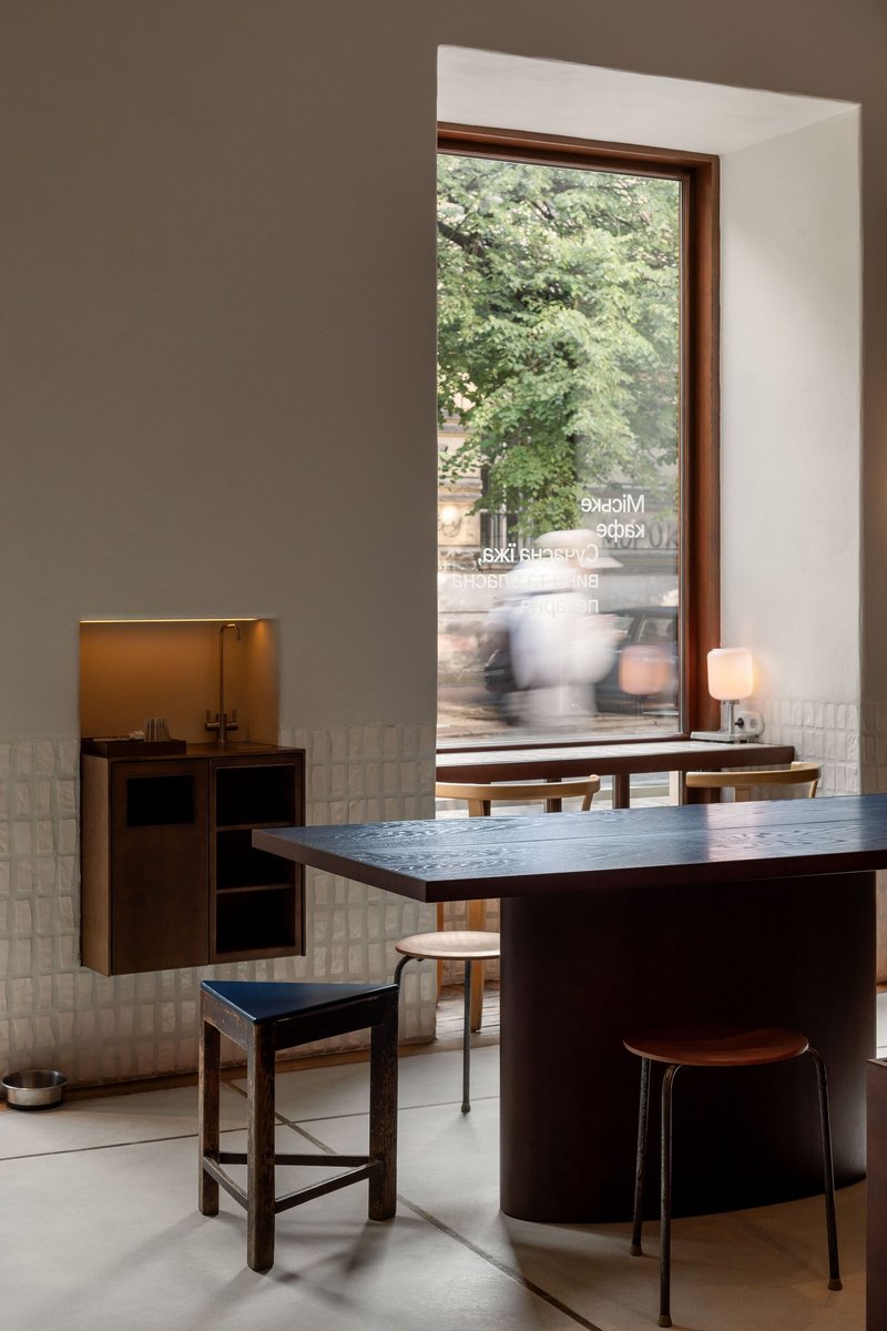 Timber-framed window with textured glass tile wainscoting and a figure passing by outside