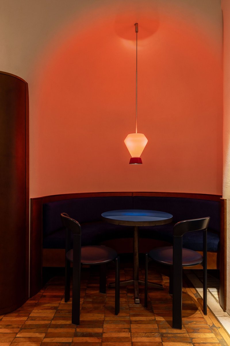 Banquette alcove with terracotta mosaic floor and single pendant lamp in warm red light
