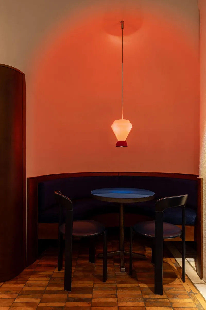 Banquette alcove with terracotta mosaic floor and single pendant lamp in warm red light