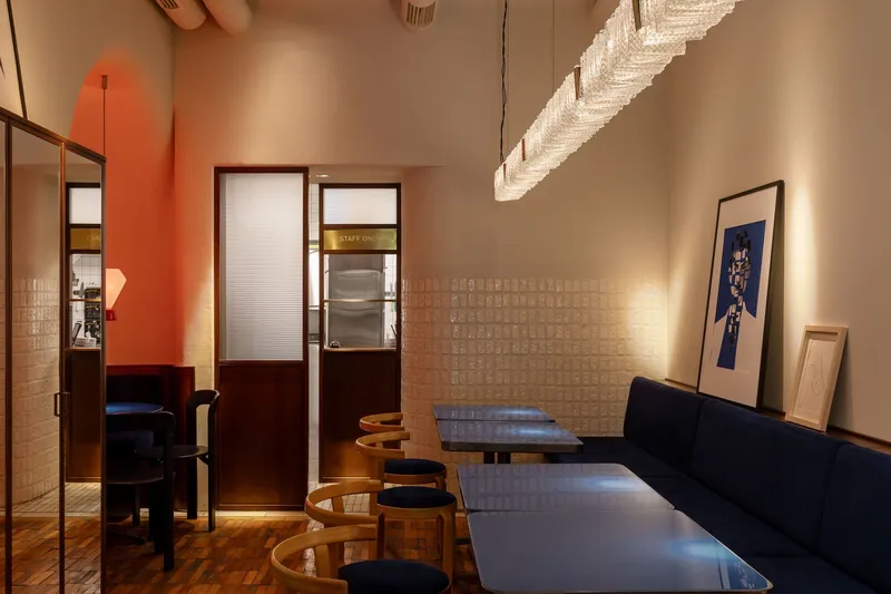 Seating nook with cream tile wainscoting and translucent glazed door reflecting an orange painted wall