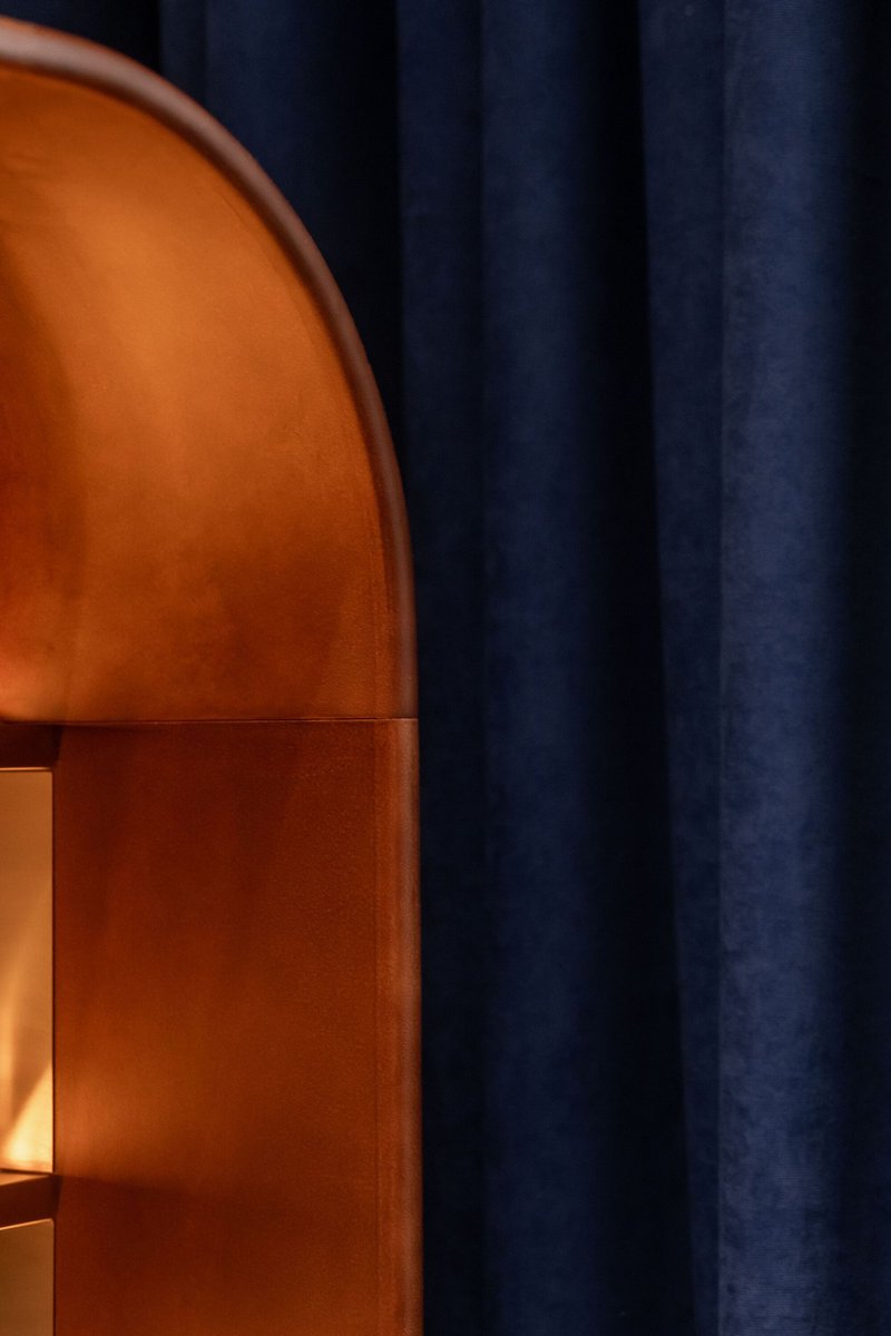 Terracotta vaulted archway framed by navy curtains in warm interior lighting