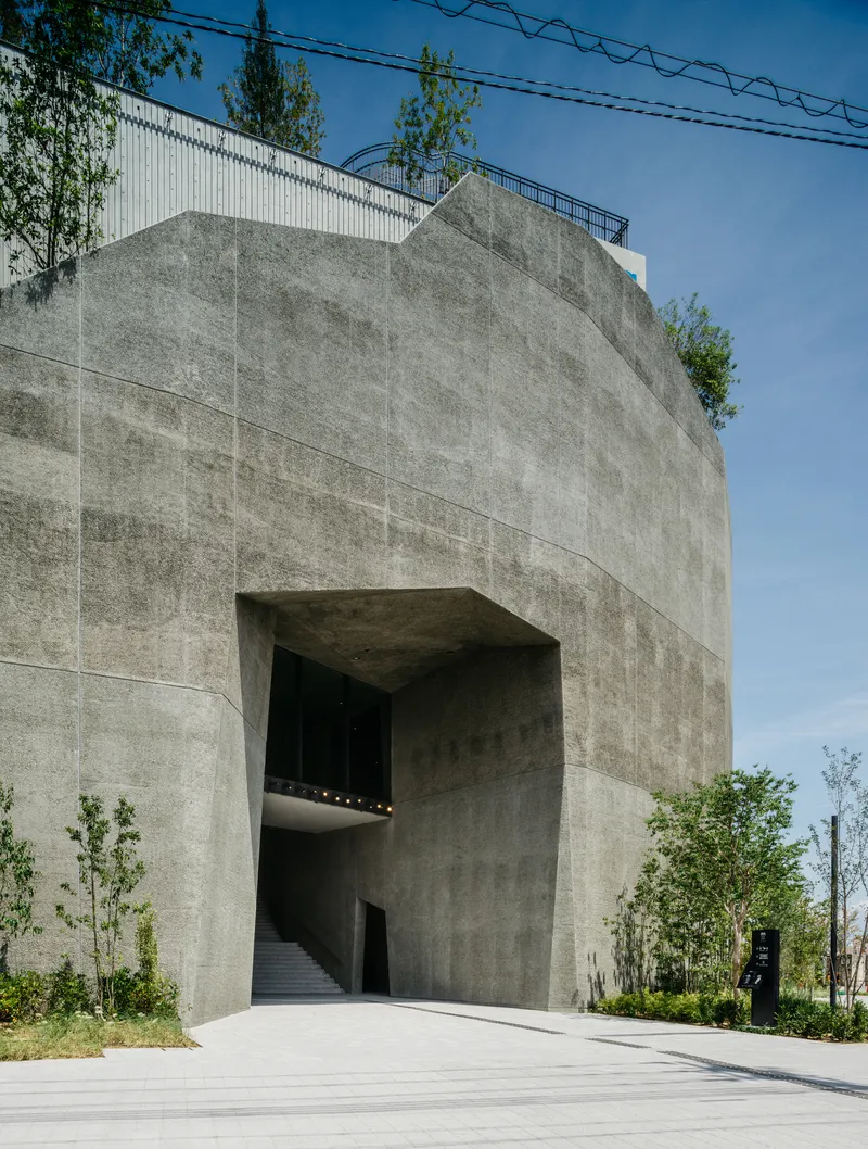 Concrete entrance portal with deep recessed opening and visible staircase under a clear blue sky