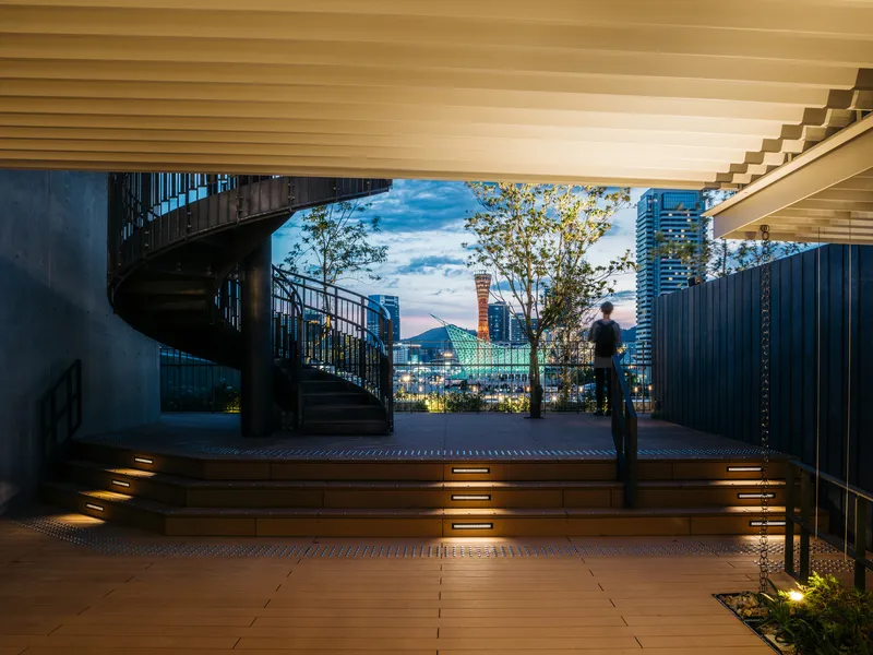 Covered deck with spiral staircase and slatted timber ceiling opening to the harbor at twilight