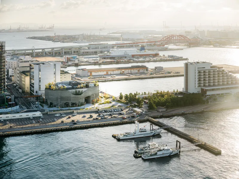 Aerial view of the rooftop terrace with planted greenery overlooking harbor waters and docked boats at dusk
