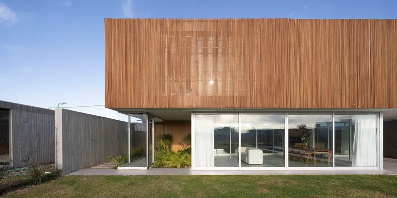 Front elevation showing timber slatted upper floor cantilevered over glazed ground level with lawn