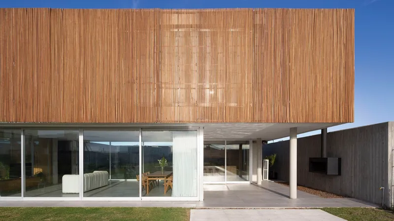 Covered terrace beneath concrete soffit with timber volume above and glass walls opening to interior