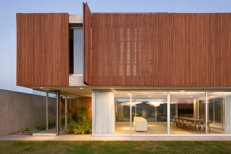 Upper-level timber screen with hinged window panel and illuminated interior at dusk