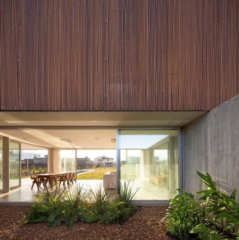 Internal courtyard with planted beds beneath timber-clad overhang and concrete boundary wall