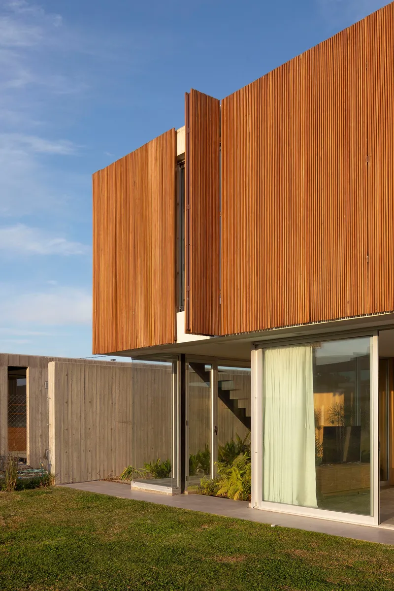 Corner view of cantilevered timber box with recessed glass walls at afternoon light