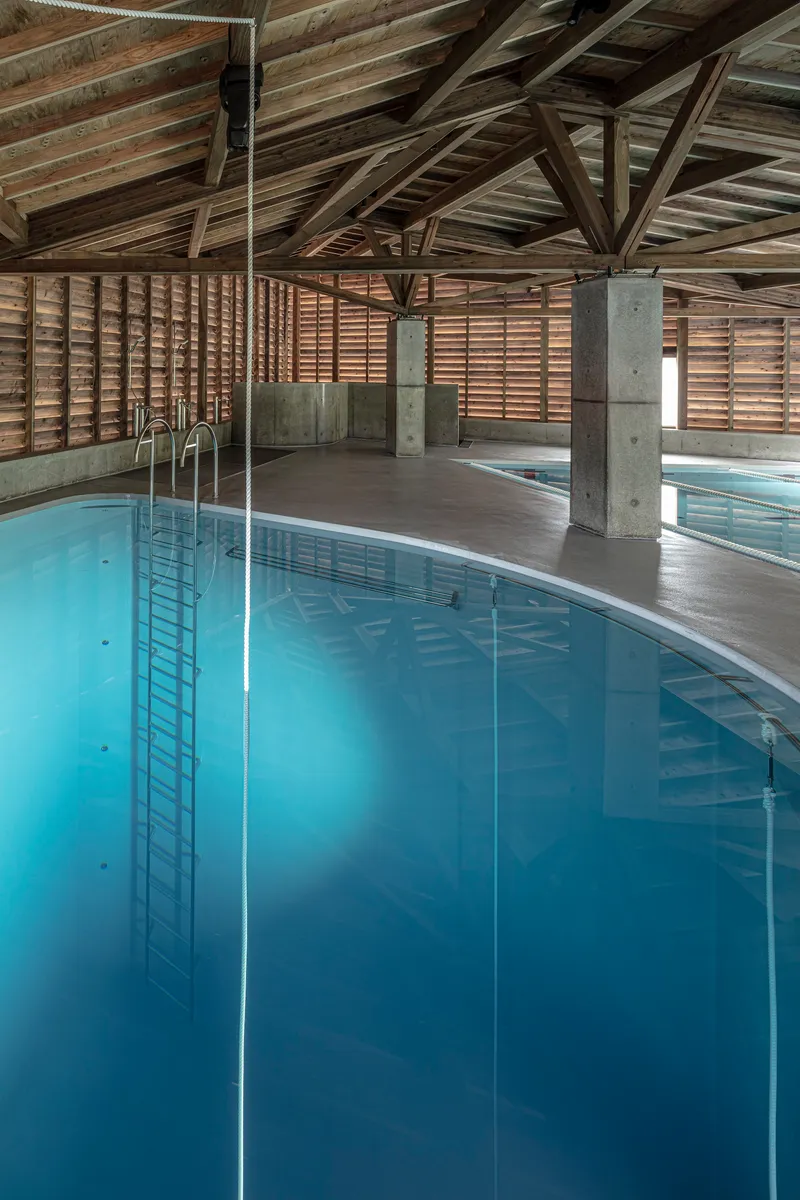 Corner of the pool showing ladder rails and horizontal slatted timber walls under timber beams